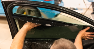 A person applying tint on the inside of car window.