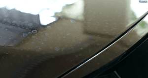 Dirty black car with dry water spots on the hood.