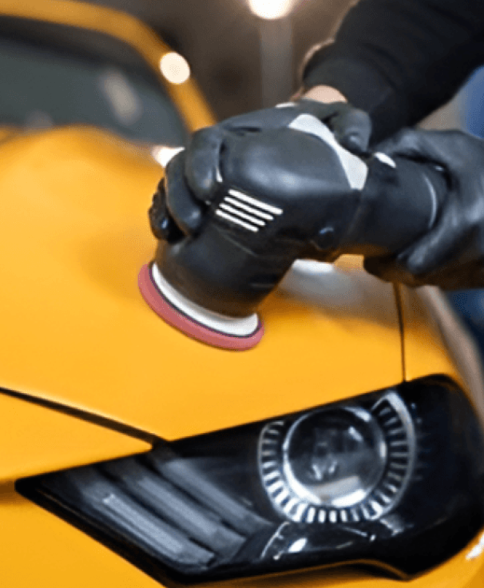 A person polishing the hood of a car.