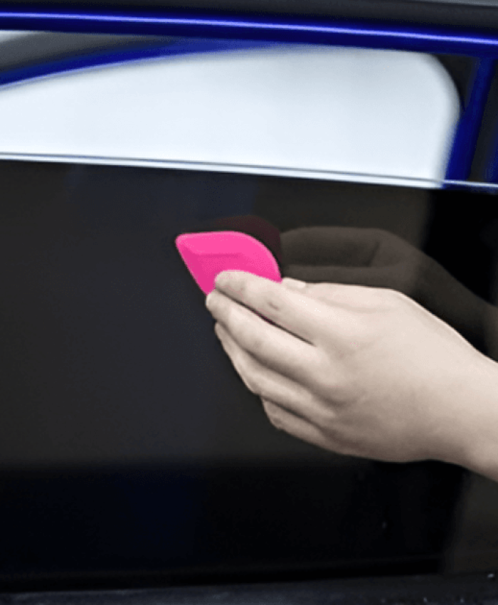 A person applying tint on car window.