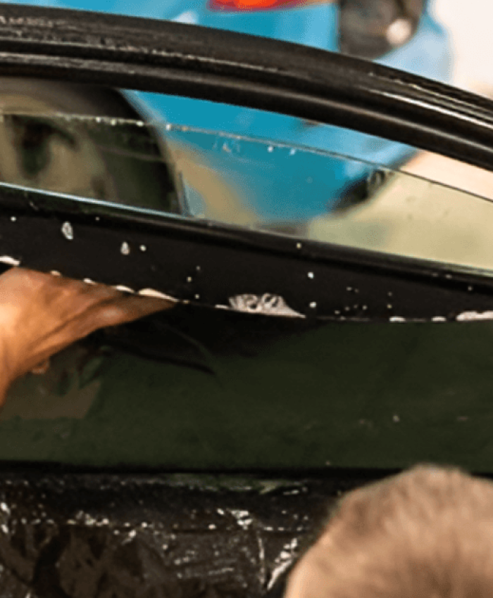 A person applying tint on the inside of car window.